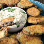 zucchini fritters on a blue plate with pine nut sauce for dipping in a small white bowl in the center